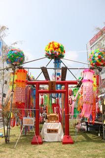 七夕まつりの芝生広場に設置された神社とお賽銭箱の周りに色とりどりの七夕飾りが飾られている写真