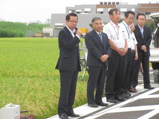 道路開通式で市長と関係者が道路端に並んでおり、市長がマイクを持ち話をしている写真