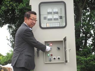 白い手袋をした市長が機械のスイッチを入れている様子の写真