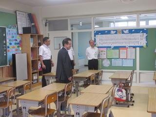 机の並べられている教室を市長と関係者の方々が視察している写真
