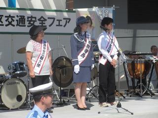 肩からタスキをかけている女性3名(1名は婦人警察の服を着用している）が舞台上に上がっている写真