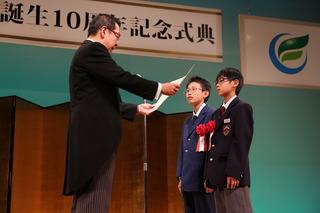 表彰を受けている男子児童2名が壇上で表彰を受けている写真
