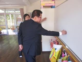 教室の白い壁を市長が触っており、保育士が説明をしている写真