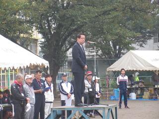 市長が朝礼台の上に立って、スタンドマイクの前で話をしている写真