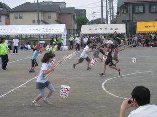 子ども達も競技に参加しており、釣竿のような棒を持って、筒状の円形の物を釣り上げて走っている写真