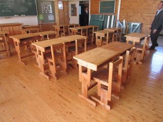 木製の机と椅子が教室に並べられている写真