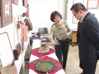 机の上に陶芸品の作品が展示されており、女性が市長に作品の説明をしている写真