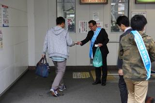 水色のタスキをかけた市長がキャンペーンのティッシュペーパーを男性に手渡しで配っている写真