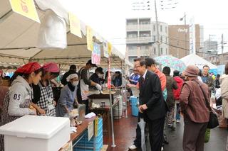 たくさんの人がにぎわう秋の収穫祭の出店の人達に話しかける市長の写真