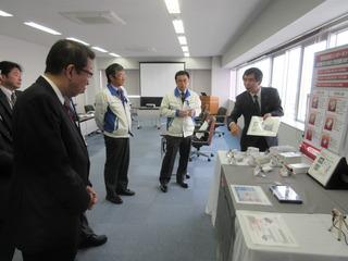 新日本無線株式会社の展示物の前で、市長が社員の方から熱心に説明を受けている写真