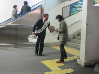 市長が駅の階段から降りて来た、市民の女性に、高齢者と自転車の交通事故防止のチラシを手渡ししている写真