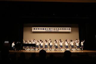 青少年を健全に育てるための市民大会で、舞台上で、ピアノの演奏に合わせて踊る女子学生の写真