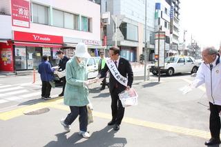 街頭で襷をかけた市長が市民の人と握手している写真