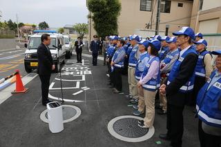 青色防犯パトカー市民パトロール隊出発式で市長が青い帽子に青いベストを着用した隊員たちの前で挨拶している写真