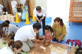 親子木工教室で小さな女の子を大人が見守りながら作成をしている写真