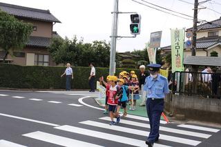 警察官に続いて青信号を並んで渡っている児童たちの写真