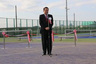 運動公園テニスコートオープニング式典にて、テニスコートに設置されているテープカットの前で、市長が話をしている写真