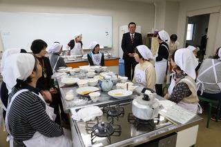 伝達講習会の試食が終わり、机の上にはお皿の料理が空になっており、前に立って講習会の参加者に市長が話をしている写真