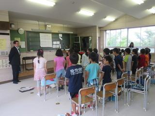 教室に見学に来られた市長の前で、児童が椅子から立ち上がって合唱をしている様子の写真