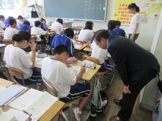 市長が授業参観をしており、悩みながら問題を解いている男児生徒の机を市長が覗き込んでいる写真
