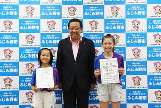 久保田 類さんと櫻井 優香さがユニフォームを着て賞状を手に持っており、市長と一緒に並んでいる写っている写真