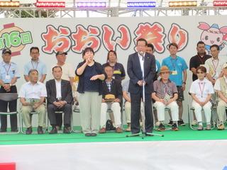 「おおい祭り」と書かれている舞台の上で、市長が話をしており、市長の隣で、手話通訳者が同時通訳をしている写真