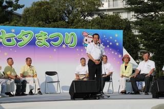 七夕まつりと書かれている舞台の上で、市長がスタンドマイクの前で話をしている写真