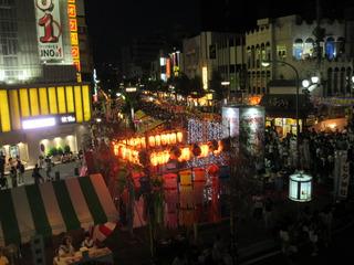 夜の通りには沢山の燈籠に火が灯り、七夕飾りで飾られて、沢山のお客さんでにぎわっている様子の写真