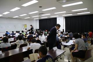 会場には沢山の机が並べられており、子ども達が沢山参加して勉強をしており、その様子を市長が見ている様子の写真