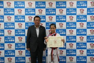テコンドー道着を着た渡部 美和さんが首にメダルをかけて、賞状を手に持って、市長と写っている写真