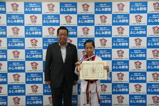 テコンドー道着を着た渡部 美和さんが首にメダルをかけて、賞状を手に持って、市長と写っている写真