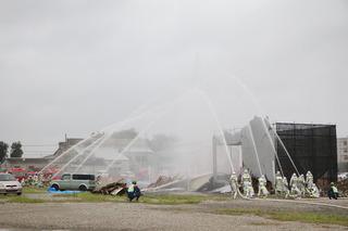 建物に向かって消防車から消火の為の放水が行われている訓練の様子の写真