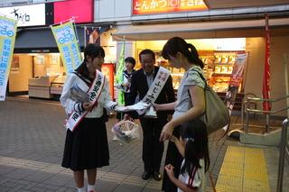 市長と女子生徒が、話かけながらチラシを子ども連れの女性に直接手渡ししている写真