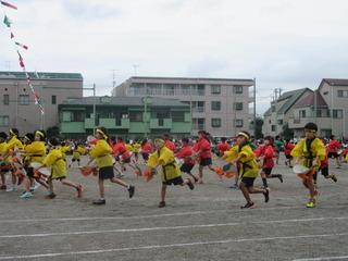 黄色い法被と赤い法被を着た児童が花笠を持って元気に踊っている写真 市内運動会（鶴ヶ丘小）