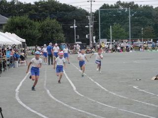 青いハチマキ、赤いハチマキを頭に巻いた男子児童が自分のコースを必死で走っている徒競走の写真 市内小学校運動会（東台小）