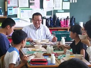 市長が子ども達のグループの班に座って、楽しそう一緒に給食を食べている写真