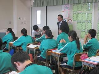 生徒達の授業風景を市長が生徒の座っている前方右横から笑顔で見ている写真