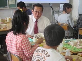 市長が子ども達と同じグループに座って給食を食べており、子どもに話かけている写真