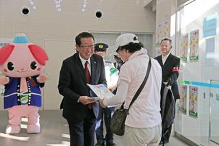 市長が市民の男性に、振り込め詐欺防止キャンペーンのチラシを手渡ししている写真