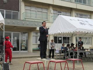 運動場の朝礼台に立って市長がスタンドマイクを使って話をしている写真