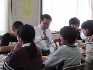 市長が子どもたちと同じグループの机に座って給食を食べている写真