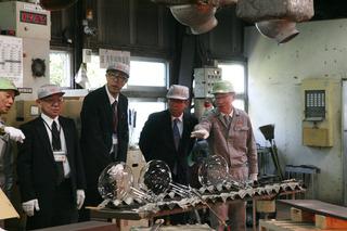 日本無線硝子株式会社の工場内でガラスができる様子の説明を社員の方から市長が説明を受けている写真