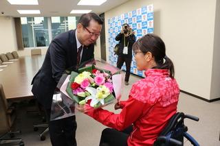 車椅子に座っている平澤 奈古選手に市長が花束を渡している写真
