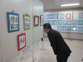 習字の書の作品が展示されており、市長が前かがみになり興味深く見ている写真