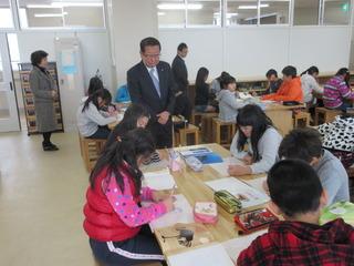 子ども達がグループに分かれて学習しており、その様子を市長が机の横に立って見ている写真