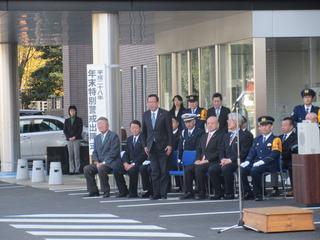 東入間警察年末年始特別警戒取締り出陣式の関係者席で、市長が並んでいる椅子から立っている様子の写真