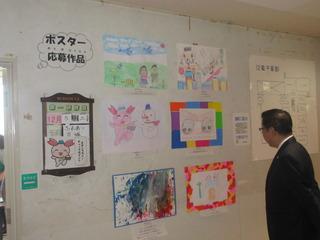 壁にポスター応募作品が貼られており、子ども達が描いたふじみんの絵画等が貼られ、市長がみている写真