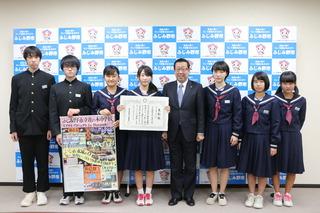 埼玉教育ふれあい賞受賞を受賞した花の木中学校の生徒の皆さんの中央の女子生徒が賞状を手に持ち、その横の二人の生徒がポスターを持ち、市長と一緒に写っている写真
