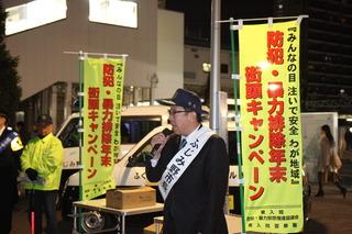 「ふじみ野市長」の白いタスキを肩にかけている市長が街頭に立って、マイクを持って話をしている様子の写真