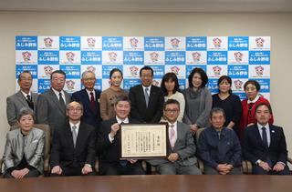 上野台小学校学校応援団の皆さんの中央に座っている方が額縁に入った表彰状を二人で手に持っており、市長も一緒に写っている集合写真